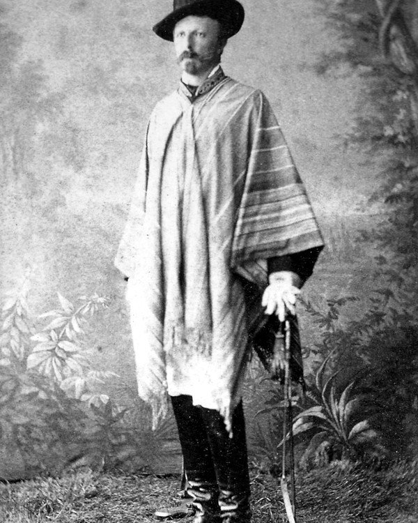 Un hombre de barba, vestido de gaucho, posa en un estudio fotográfico